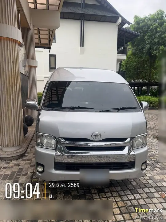 รถตู้ Toyota Commuter สีเงินจอดรอรับลูกค้าหน้าโรงแรมตอนเช้า