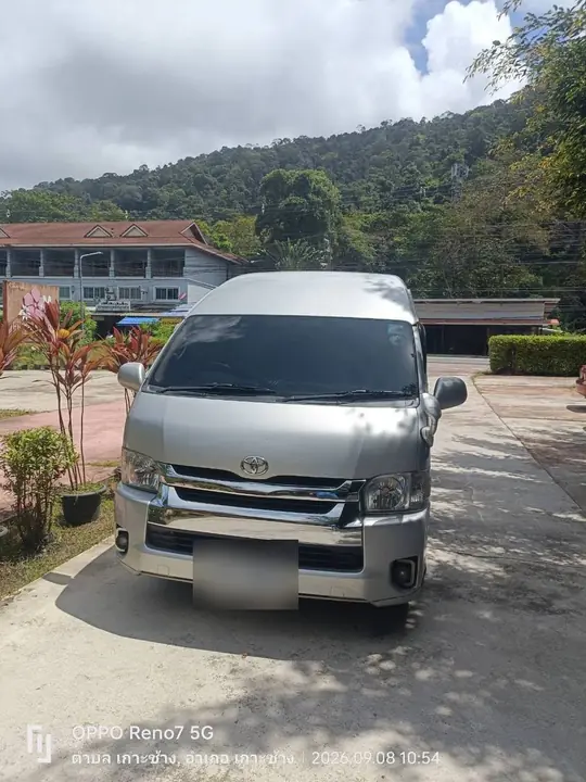รถตู้ Toyota Commuter สีเงินจอดรอลูกค้าบนเกาะช้าง มีภูเขาเป็นฉากหลัง