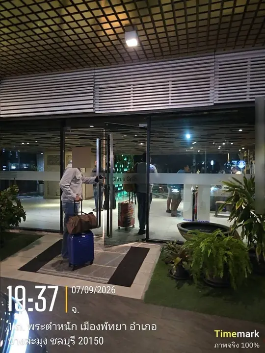 ผู้โดยสารพร้อมกระเป๋าเดินทางที่ทางเข้าโรงแรมตอนกลางคืน — พัทยา